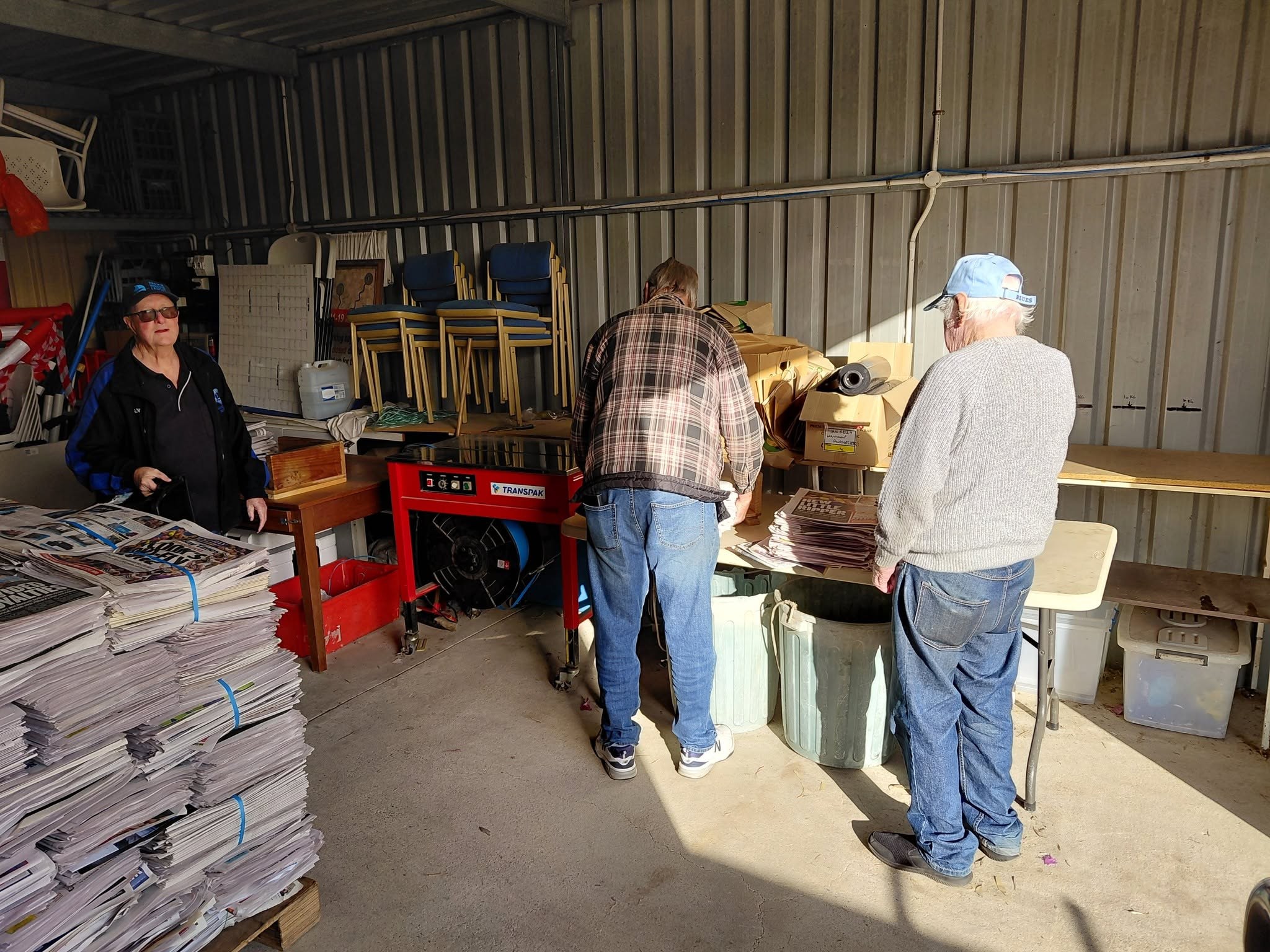 Club volunteers working together to bundle newspapers in the recycling shed